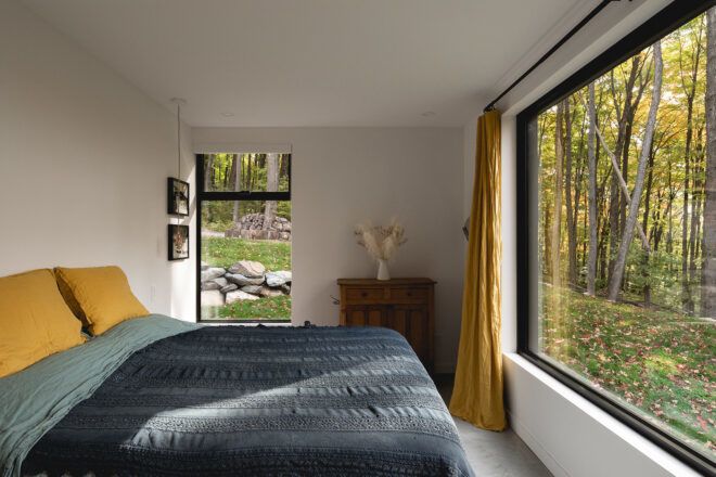 A bed facing a window with another window on the side