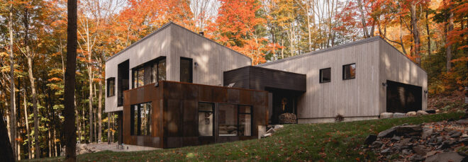 A two-story home surrounded by trees with red and orange leaves