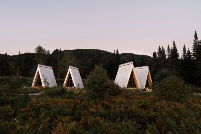 Four triangle tents set up along a green landscape