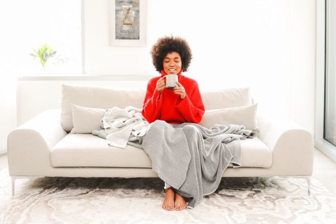 Woman modeling gray blanket on couch