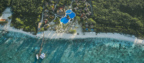 Aerial view of hotel surrounded by forest near a sea