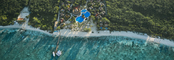 Aerial view of hotel surrounded by forest near a sea