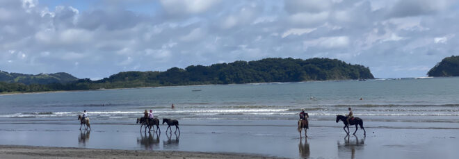 Beach in Costa Rica with people atop horses