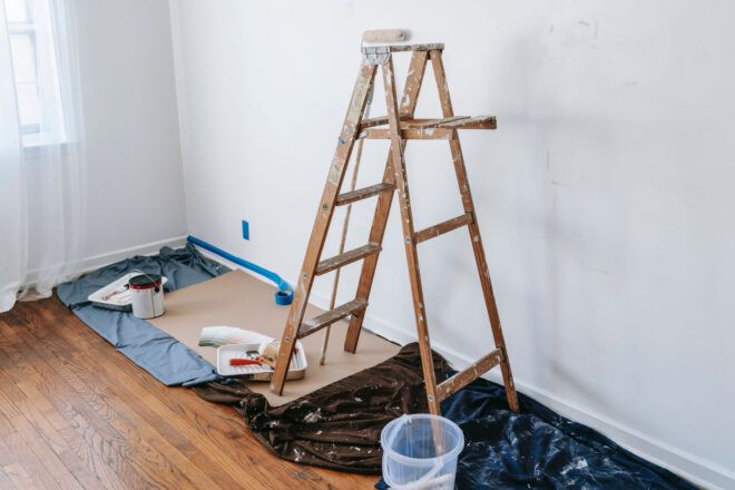 A ladder in a room being painted white