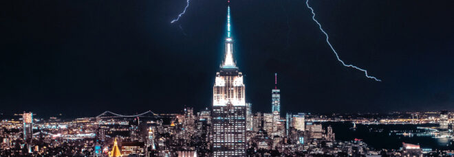 Nighttime of the New York skyline with skyscrapers lit up during a lightning storm