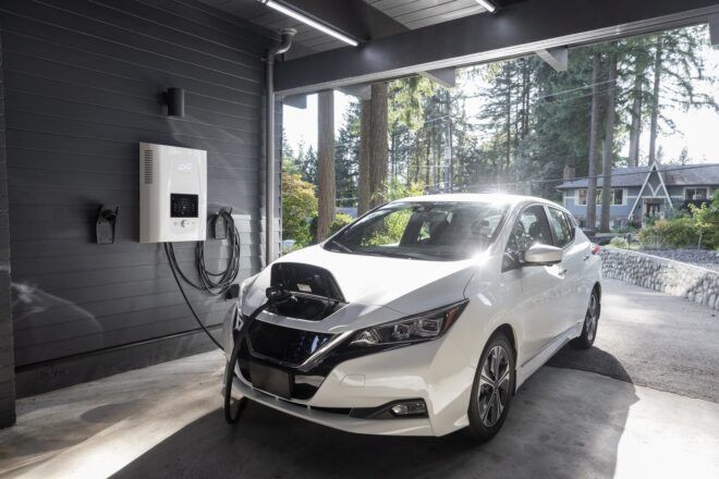A white vehicle being plugged in from the head to a electric charging port