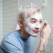 A man with a white cream smeared all over his face presumably washing his face with a soap