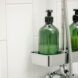 Two green shower bottles in a shower container against white tiles