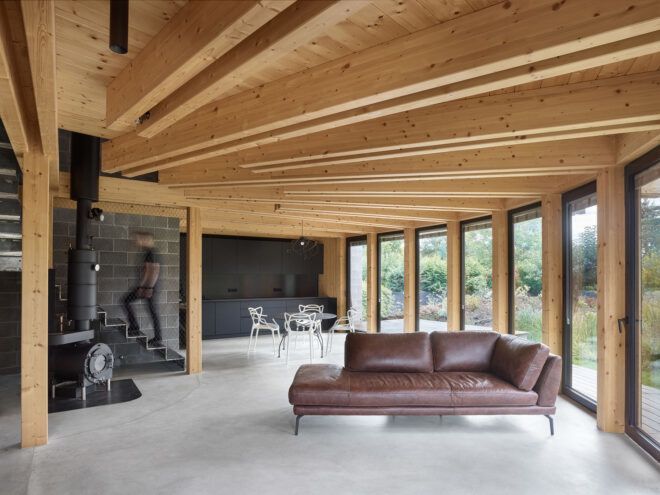 A living room and dining room space with wooden ceilings and a window paneled curved wall
