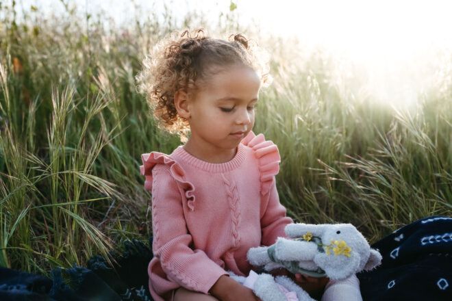 Child examining stuffed elephant animal in a field