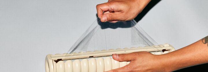 Two hands holding a stretch nonplastic and extending it out of its canister