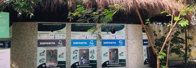 A recycling center with three posters of information on the side of it and a leaf roof
