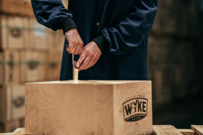 A person checking a cheese in a square bin
