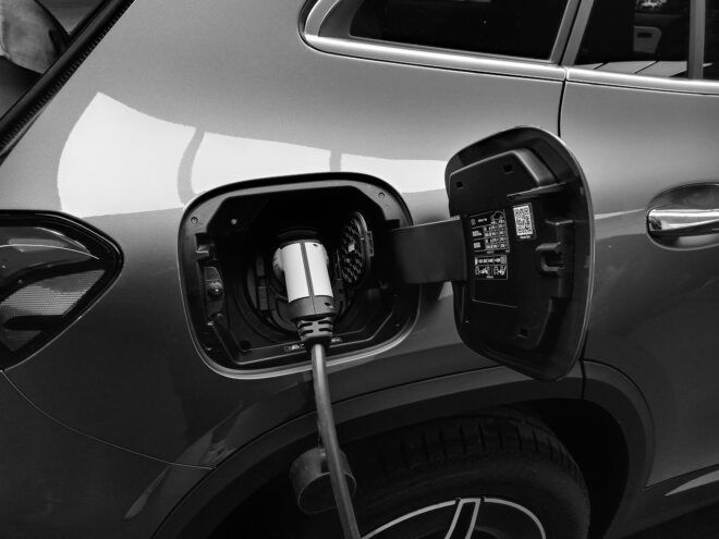 A gray car being plugged into an EV charger