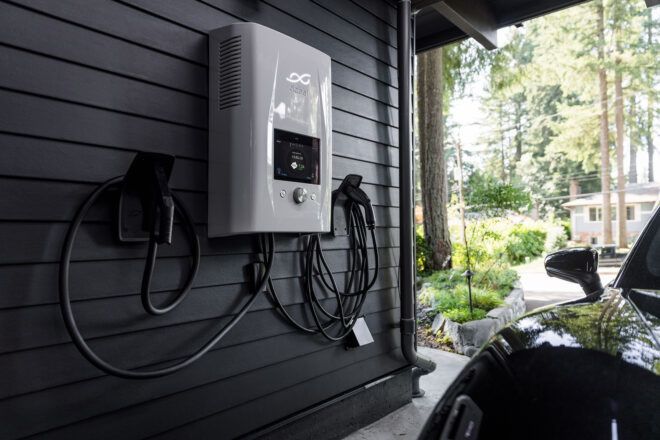 A white charging port next to a car parked inside a garage
