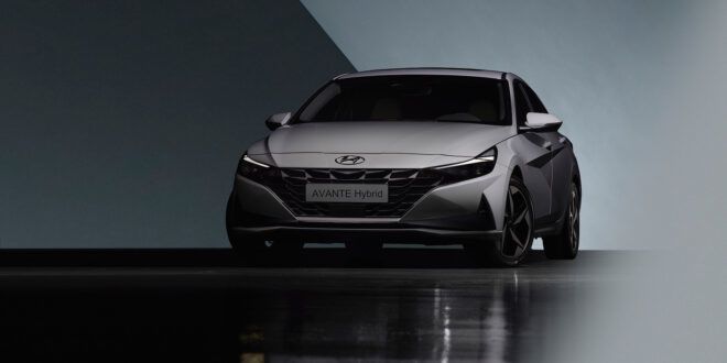 A gray car on a black floor against a gray backdrop