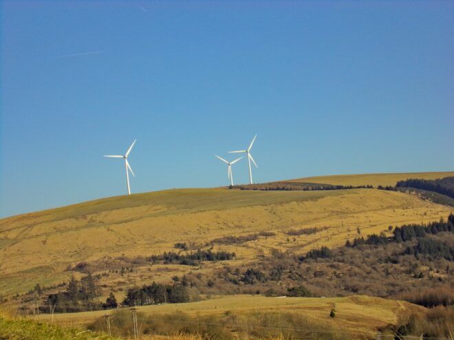 Three wind turbines on a yellow grass hill