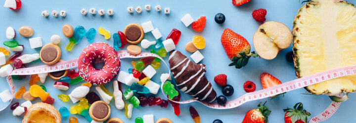 Sweats and fruits laid out on a blue background with a tape measure