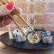 Hand holding chopsticks picking up a plant-based maki roll