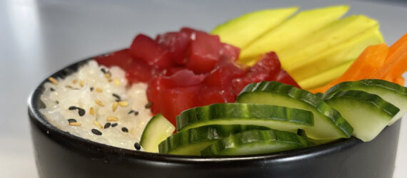 Chopsticks picking up a piece of plant-based tuna from a plant-based poke bowl