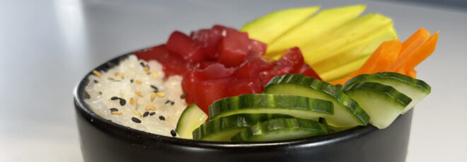 Chopsticks picking up a piece of plant-based tuna from a plant-based poke bowl