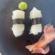 Plant-based white fish nigiri with wasabi and pickled ginger on a black plate