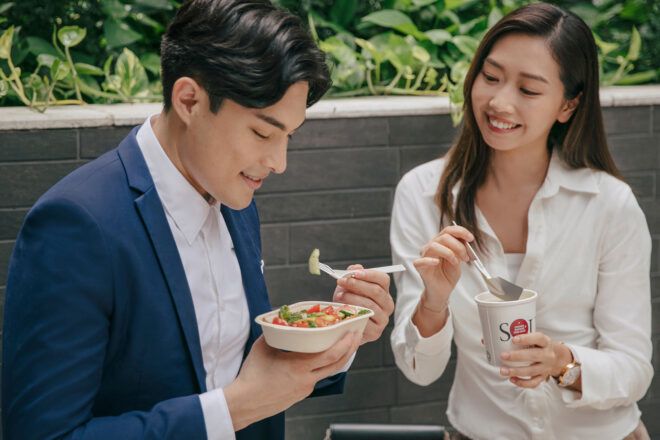 Two people eating lunch on a bench