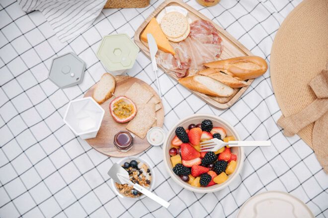 A picnic spread of a fruit bowl, baguettes and plates with utensils