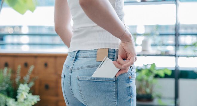 A perfume placing a flat object into their back pocket