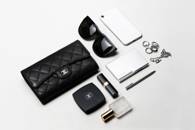 An array of items, a purse, sunglasses, phone, a metal container, lipstick, perfume
