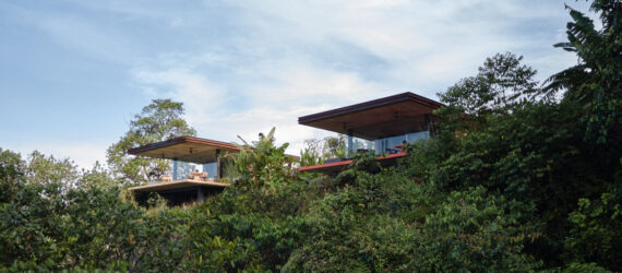 View to two villas cantilevering off a hillside in the jungle