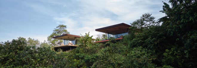 View to two villas cantilevering off a hillside in the jungle
