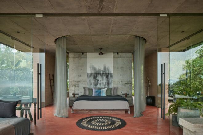 Interior of a villa facing the bed with a wrap-around mosquito net and traditional Latin American rug