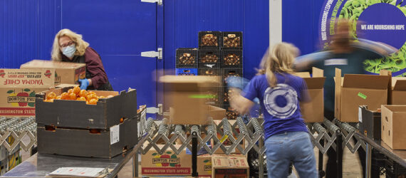 Three people packing boxes in a food pantry