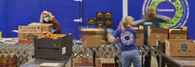 Three people packing boxes in a food pantry