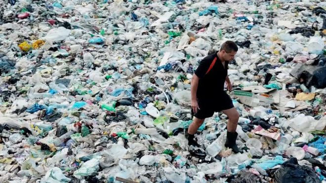 A man stepping through a pile of trash that covers the entirety of the image