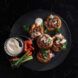 Open-faced pastries with fresh veggies and a dip cultured meat mince on a black plate with veg
