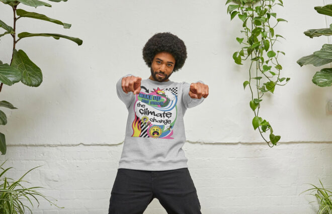 A man with an afro pumping his fists to the camera and wearing a gray sweater