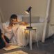 A person leaning on a bed with a night lamp turned on