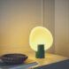 An obscure circular lamp stuck into a cylindrical base on a nightstand