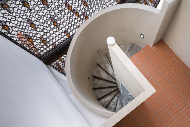 A spiral staircase next to a sheer circular screen wall