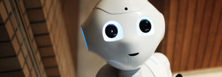 A white robot with eyes and a mouth staring
