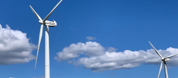 Two wind turbines against a blue and cloud sky