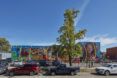 A mural outside of a food pantry with cars parked along the street