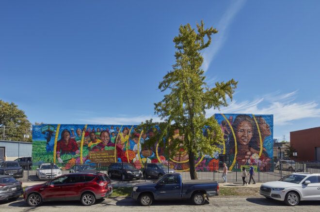 A mural outside of a food pantry with cars parked along the street
