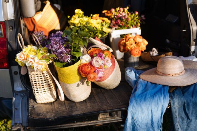 A car trunk packed with woven baskets filled with flowers