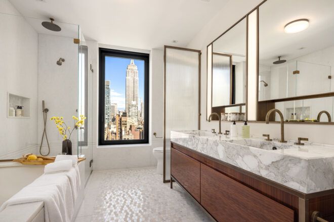 A bathroom with open window overlooking skyscrapers