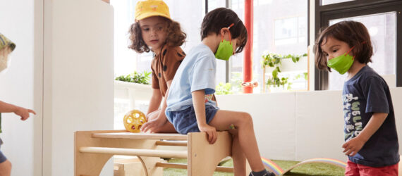 Four preschoolers playing with wooden playground equipment