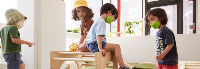 Four preschoolers playing with wooden playground equipment