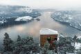A cabin that overlooks an icy river and mountain range